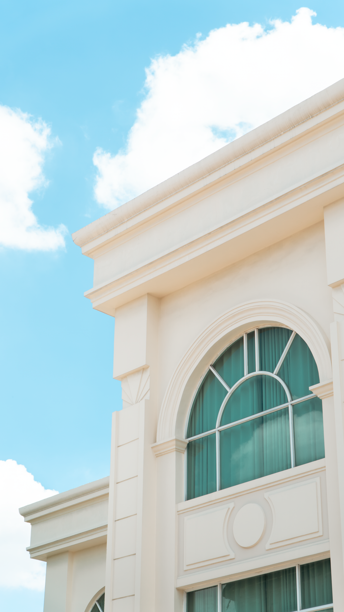 Close-up of a classic white building with arched windows against a bright sky.